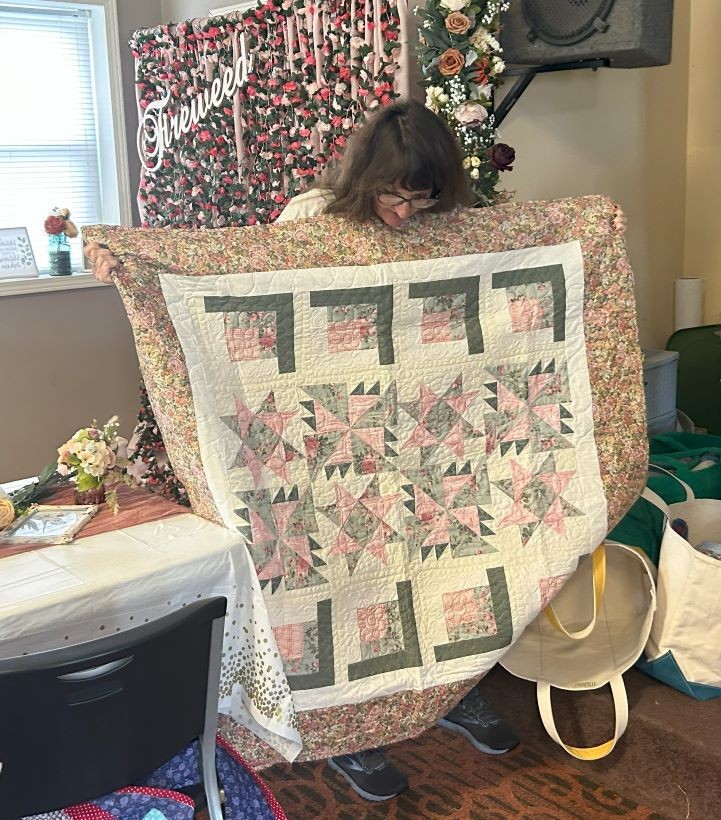 Woman holding up quilt